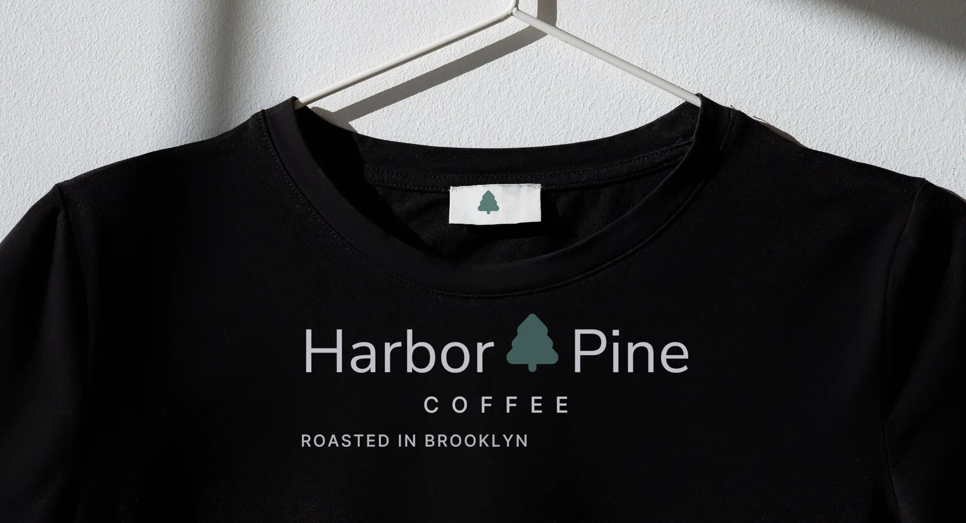 Harbor & Pine Coffee logo on black tee on a hanger