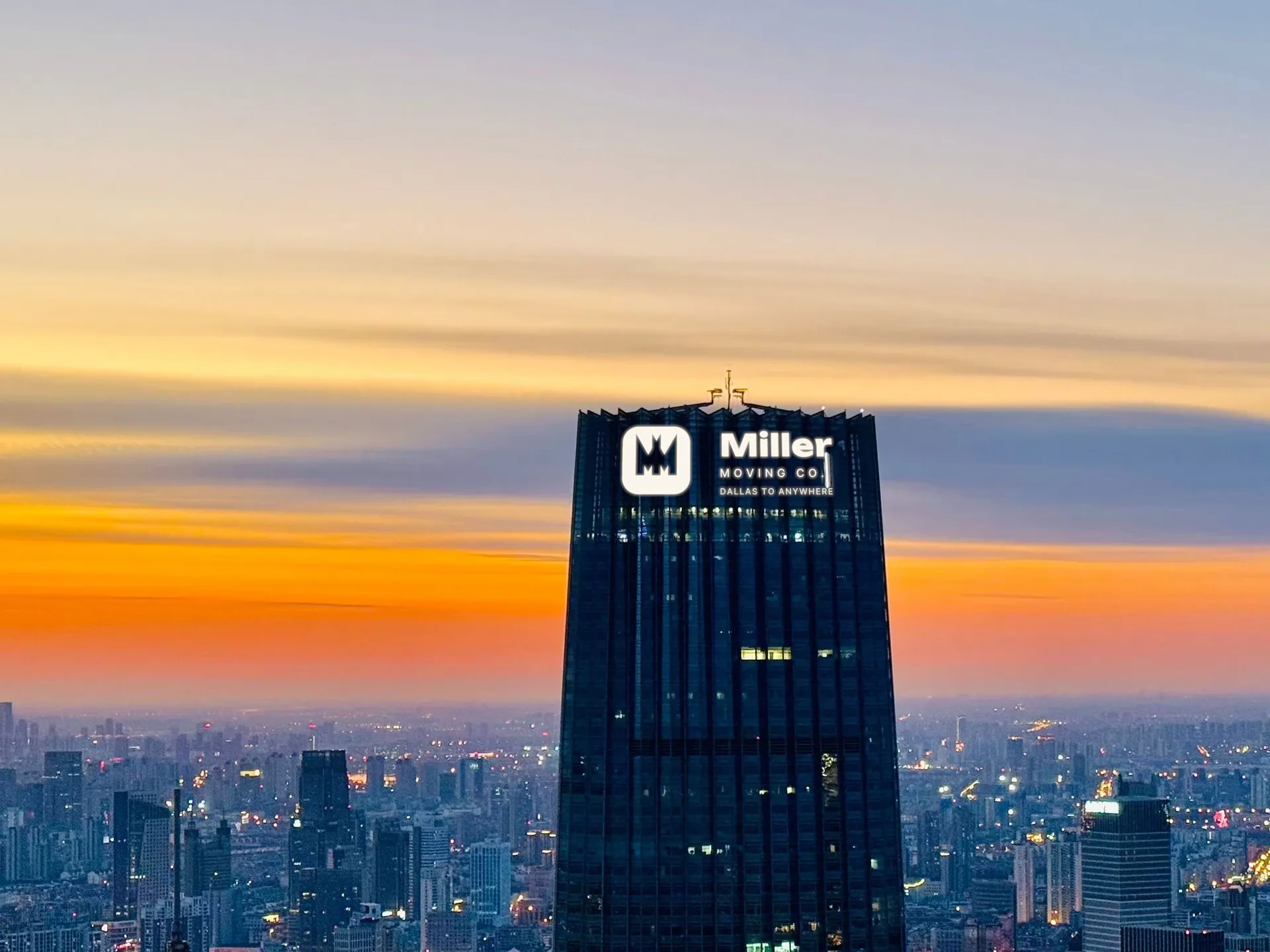 Miller Moving Co. logo on glass tower at dusk